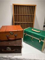 Four items together including three cases (brown leather, dark brown Polaroid leather, green Samsonite) and wooden organizer with slots