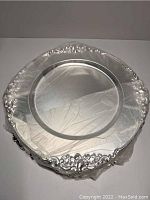 Silver plated charger wrapped in cling wrap with ornate edge detail