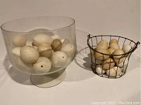 Photo of multiple real eggs of two sizes, some hollowed, arranged inside a glass bowl and a wire basket.