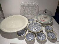 Photo showing the large white ironstone bowl, square glass platter, cake stand with acrylic lid, and smaller patterned bowls arranged together