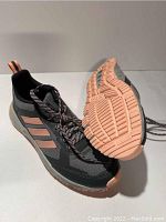 Pair of black Adidas running sneakers with peach accents, showing outer and sole views