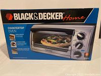 Box of Black & Decker Home countertop oven showing front with image of oven cooking pizza and Black & Decker branding.