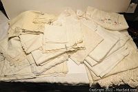 Overview of folded vintage linens including placemats, napkins, and tablecloths showing various edges and embroidery details