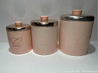 Three pink nesting metal canisters labeled Coffee, Sugar, Flour with rose gold metal lids