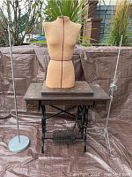 Full view showing all items together: antique sewing machine table, vintage dress form on top, two tall metal stands sides