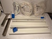 Photo showing two ENKLAV pendant lights in white still in original sealed packaging, four white Ribba wall shelves, and two white metal IKEA brackets lying flat on a surface.