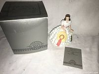 Porcelain figurine of Vivien Leigh as Scarlett O'Hara from Gone with the Wind displayed with original box and pamphlet on white surface.