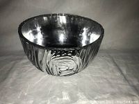 Side angle view of shiny, hammered silver-tone metal bowl showing textured swirl pattern on exterior.