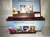 Two unopened boxes of curved glass photo frames showing packaging and sample photo displays