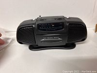 Mini black Suntone battery-operated radio with twin speaker system, analog AM/FM dial on front, placed on a white surface.