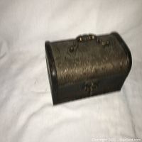Small wooden decorative chest covered with embossed faux leather, featuring a top handle and front clasp, photographed on a white background
