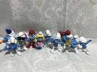 Lot of 10 Smurf figures showing various characters with white and red hats, some holding accessories like mirror and pan.