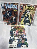 Three Venom comic books issues 1, 2, and 3 displayed together in protective sleeves with visible colorful covers.