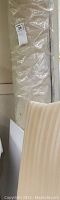 Rolled beige area rug sealed in original plastic packaging with lot number sticker.