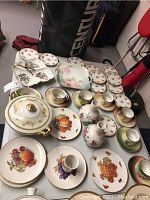 Overview of china set including fruit plates, cups, saucers, pitchers, and serving dishes arranged on table