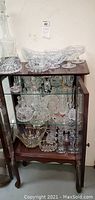 Full view of the collection inside and on top of a wooden display cabinet showing a variety of crystal bowls, candle holders, candy dishes, and a large decanter on top.