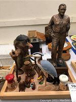 Photo showing a variety of wooden figurines including a troll, bird, salt and pepper shakers, and small animal figures arranged on a wooden tray.