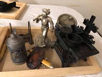 Overview of all lot items on wooden tray with stove model, stein, figurine, razor, and badges