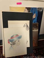 Four signed original art pieces leaning against a wall, showing fashion illustrations and figural paintings, some unframed with visible staining.