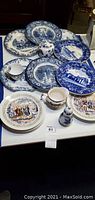 Set of blue and white transferware plates including one cup, small jug, and salt shaker.