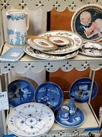 Full view of shelf showing ceramic plates, Jasperware items, Wedgwood pitcher and other collectible plates including Royal Copenhagen Christmas plates.