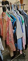 Photo of women's clothing hanging on rack showing variety of tops and blouses in different colors and patterns