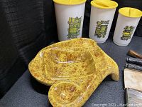 Large mid-century yellow speckled ceramic ashtray with three vintage canisters in background