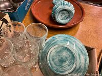 Six Princess House etched glass goblets with floral/ornate engraving in a box, alongside turquoise ceramic bowl and ceramic pitcher.