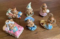 Overview photo of all six Pendelfin bunny figurines arranged on wooden floor, showing various poses and costumes.
