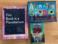 Photo of the open box showing This Book is a Planetarium and Animation Studio kit box and Dog Man 3D book.
