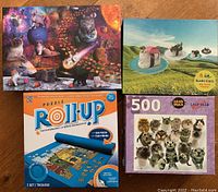 Four items including three cat-themed jigsaw puzzles and one blue puzzle roll-up mat. Puzzles feature different cat images and sizes.
