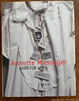 Front cover of the hardcover art book showing a white garment with tags and book title.