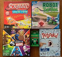 Lot of 5 kids games including Scrabble Junior, Robot Turtles, 5-Minute Marvel, Dutch Blitz, Pictureka!. Boxes shown laid flat, colorful artwork and branding visible.