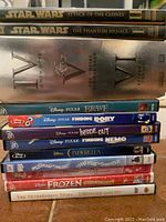 Stack of DVDs and Blu-rays showing Star Wars IV, V, VI on Blu-rays and Star Wars I and II on DVDs with Disney Pixar titles and other kids movies below.