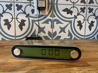 Front view of Lexon digital clock radio showing LCD screen with digital time display and two control knobs