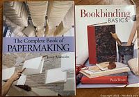 Photo of two instructional books: The Complete Book of Papermaking and Bookbinding Basics, placed side by side on a wooden surface.