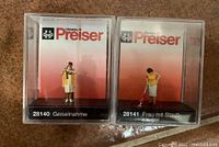 Preiser HO scale figures in unopened plastic display cases showing the two miniatures: hostage situation and woman vacuuming.