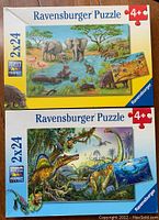 Front view of two Ravensburger puzzle sets boxes featuring wildlife and dinosaur scenes for kids.
