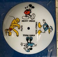 Top view of glass globe showing front face with colorful 1970s style Disney characters Mickey Mouse, Minnie Mouse, Donald Duck, and Pluto arranged around center hole
