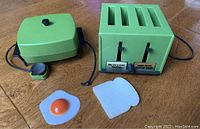 Image showing avocado green electric frying pan, toaster unit with four slots, plastic fried egg and foamboard bread slice.