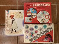 Three boxed items: 1960s Spirograph sets in red and blue boxes and a Holly Hobby puzzle box with artwork of a girl holding basket.