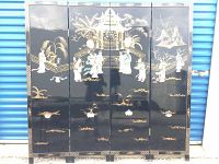 Full front view of the black folding dressing screen with painted and applique decorated panels showing Asian scenes and figures.