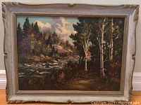 Full view of the framed landscape painting with river, trees, and sky.