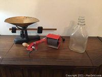 View of the Gratex red manual grinder, vintage scale with brass pan, and one clear glass bottle.