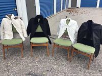 Four women's jackets/coats displayed on green chairs outside near storage units.