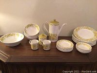 Full view of dinnerware set including bowls, plates, mugs, coffee pot, and sugar bowl with floral and abstract pattern.