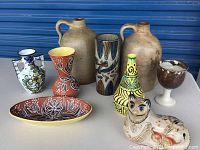 Photo of entire pottery collection showing all nine pieces arranged on a table against blue background.