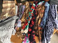 Several scarves of various patterns and colors displayed side by side showing fringes and different fabrics.