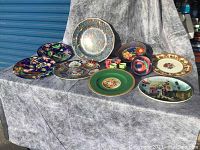 Overview of assorted decorative serving plates and one bowl, various floral and scenic designs including Royal Doulton platter