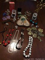 Overall view of lot on table showing necklaces, figurines, rings, pyramids, brooch, fragrance box and dish